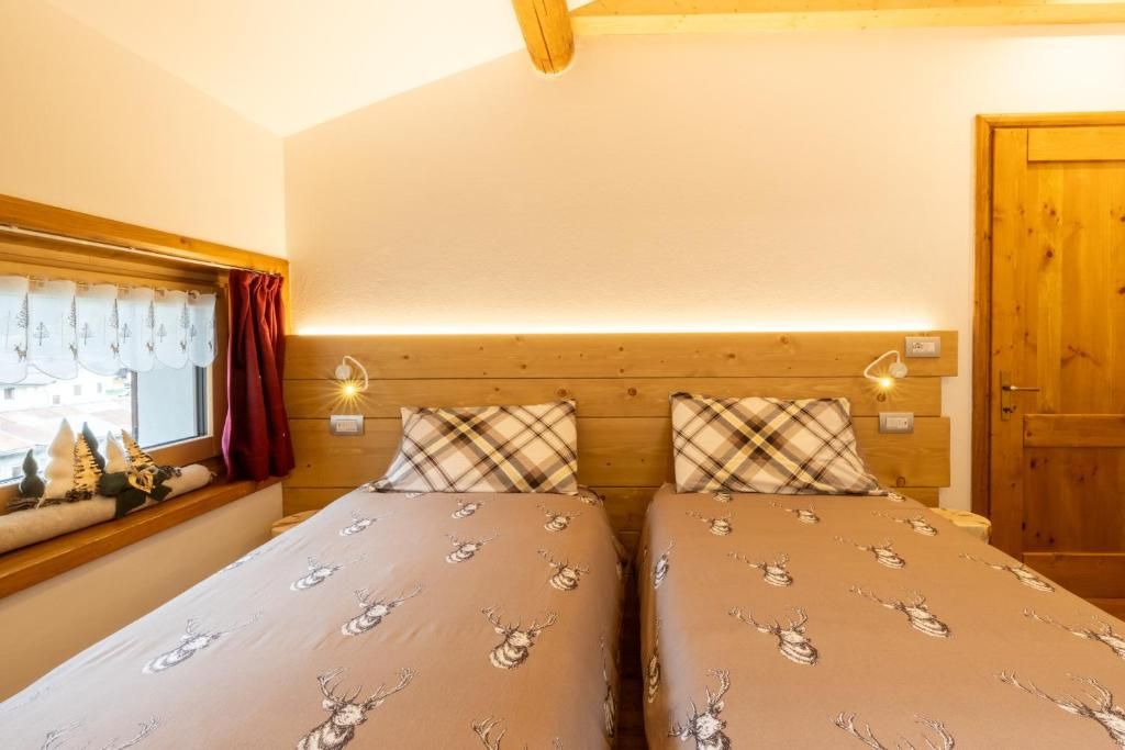 Una habitación con dos camas, cada una con cabecera y almohadas a juego, una ventana con cortinas y una puerta de madera.