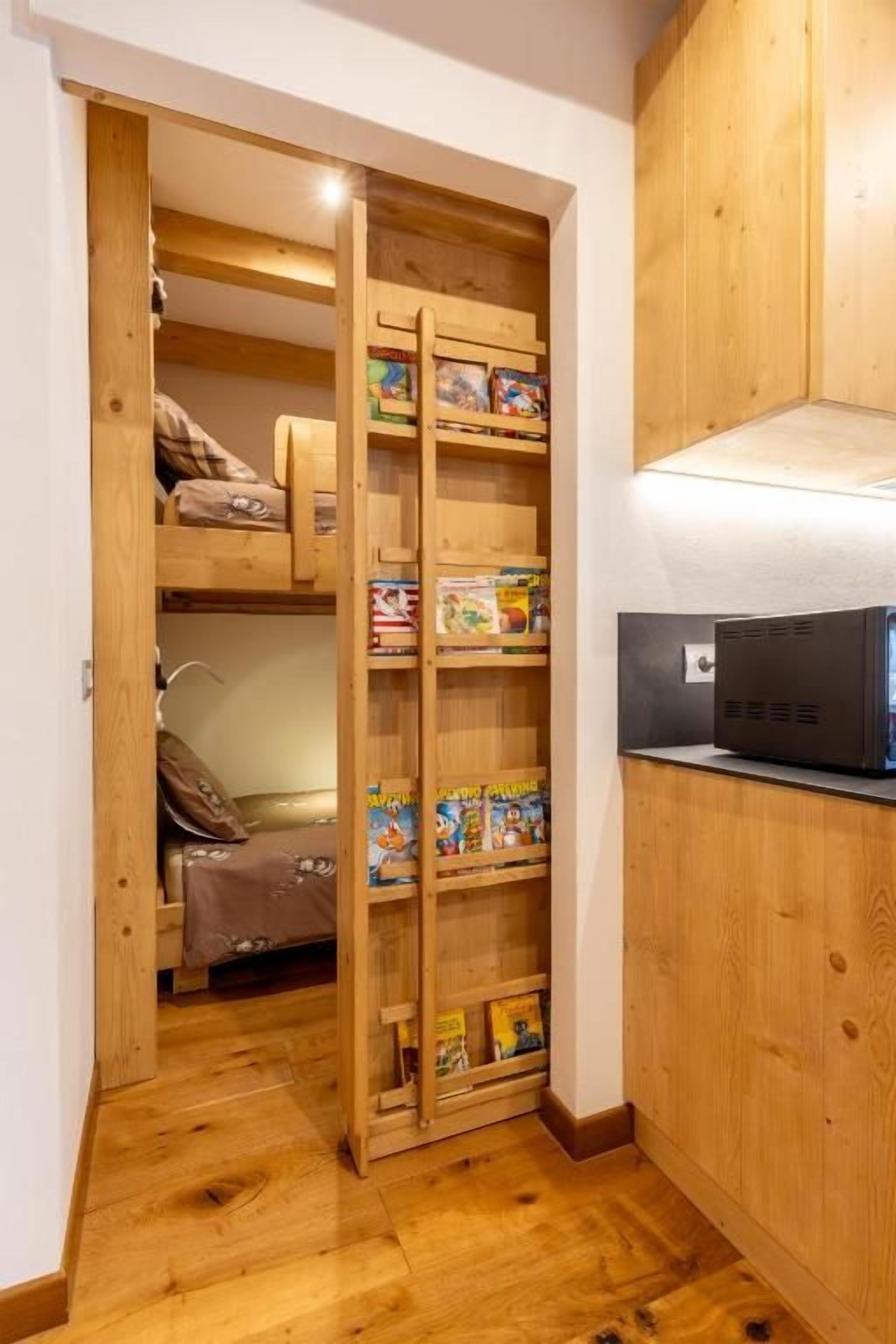 Un armario de madera con estantes que guardan libros y una cama con una manta.