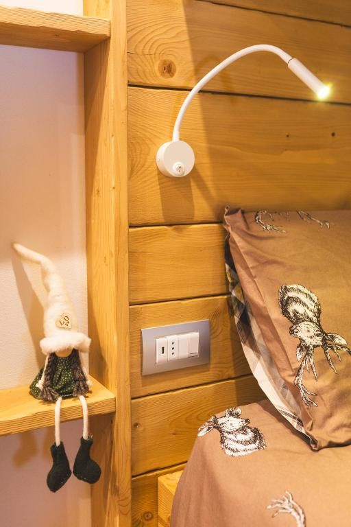 Ein hölzernes Bett mit einem braunen Kopfkissen und einer weißen Lampe.