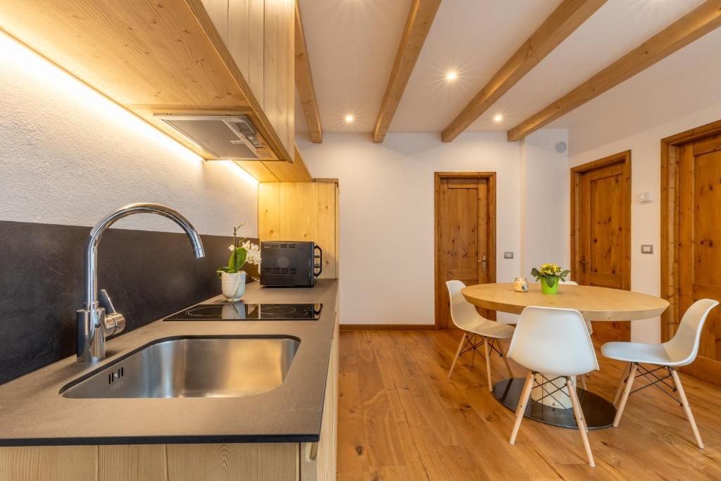 Una cucina moderna con lavello in acciaio inossidabile, mobili in legno e un tavolo rotondo con sedie bianche.