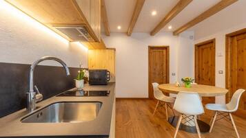 Una cucina moderna con lavello in acciaio inossidabile, mobili in legno e un tavolo rotondo con sedie bianche.