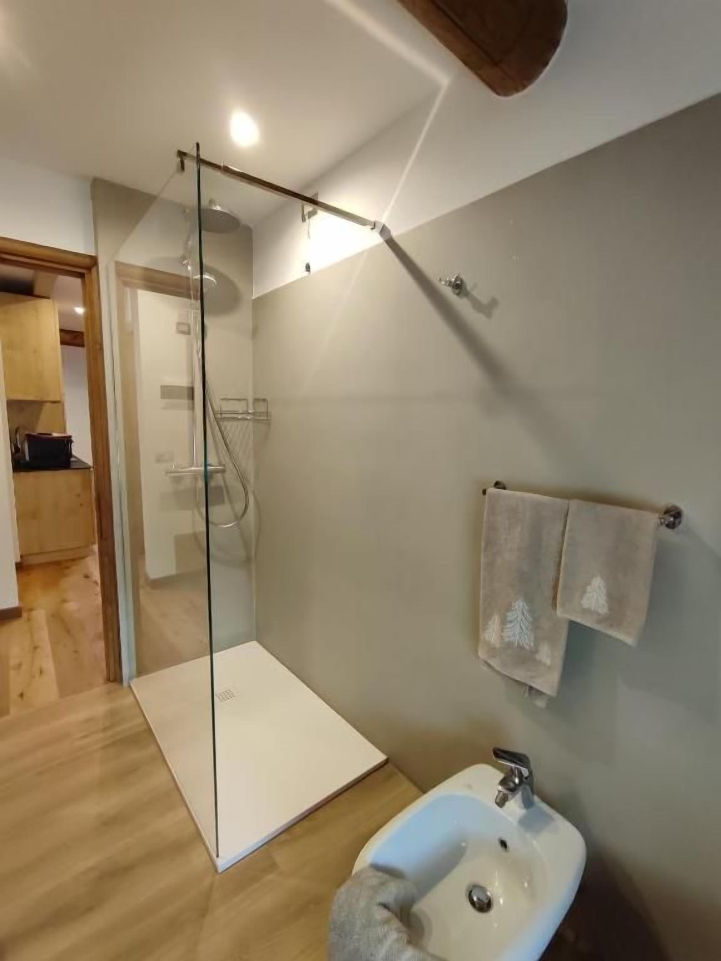 Ein modernes Badezimmer mit Duschkabine aus Glas, Waschbecken und Handtuchhalter.
