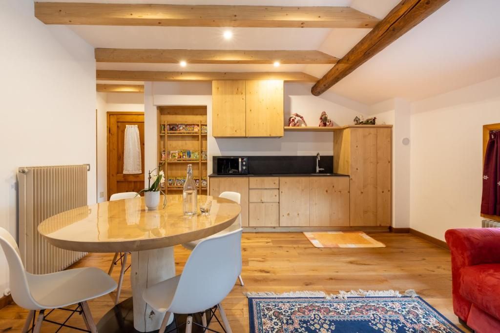 Un coin repas avec une table ronde et des chaises, une cuisine avec des meubles en bois et un canapé rouge.