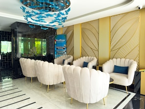 A modern lobby with a chandelier, seating area, and a decorative wall. - Qoople Aria 4 - Cozy 1-bedroom apartment in Alanya (Alanya)