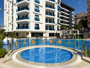A modern hotel with a swimming pool featuring decorative shells and starfish. - Qoople Aria 4 - Cozy 1-bedroom apartment in Alanya (Alanya)