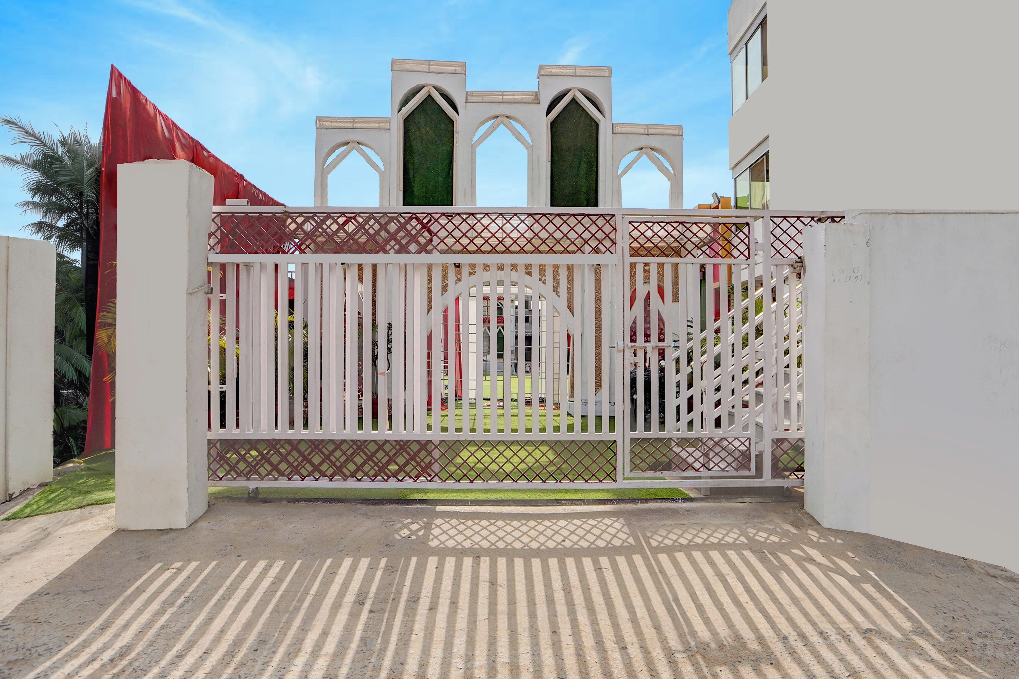 A gated entrance with a decorative gate and a red flag on the left.