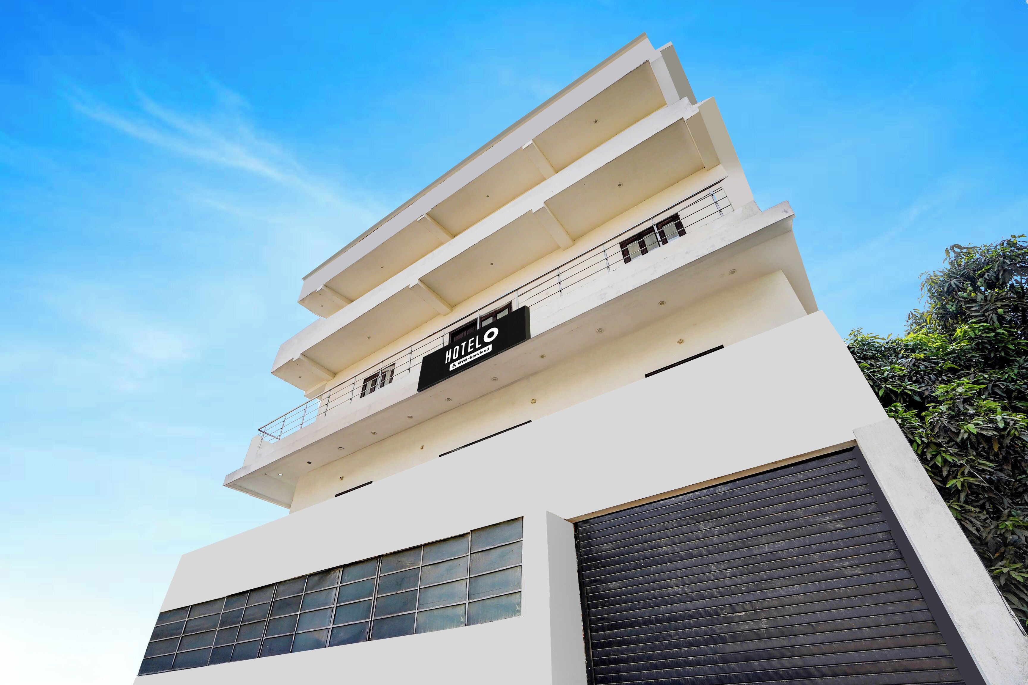 A multi-story hotel with a flat facade, balconies, and a sign indicating it is serviced by OYO.
