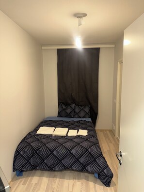 Makuuhuone, jossa on sänky, kattovalaisin ja ovi.