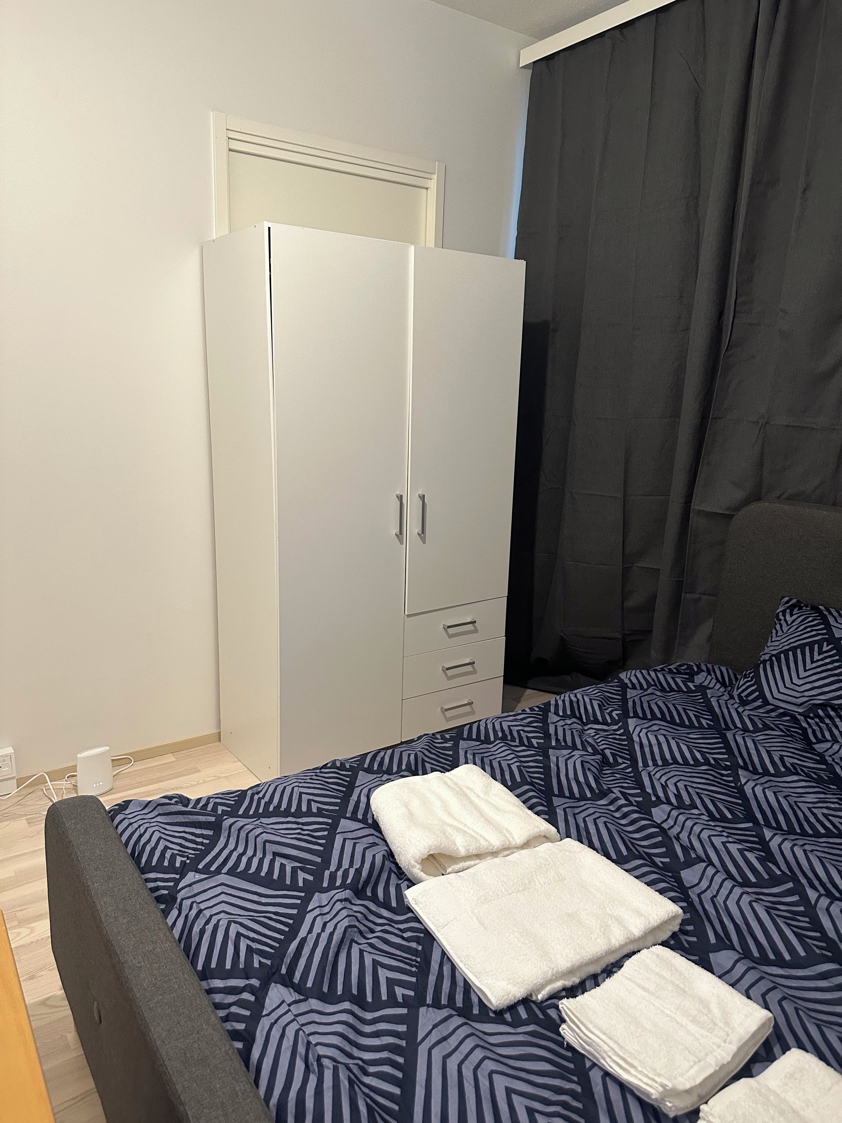 A bedroom with a bed, a wardrobe, and a bedside table.
