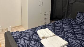 A bedroom with a bed, a wardrobe, and a bedside table.