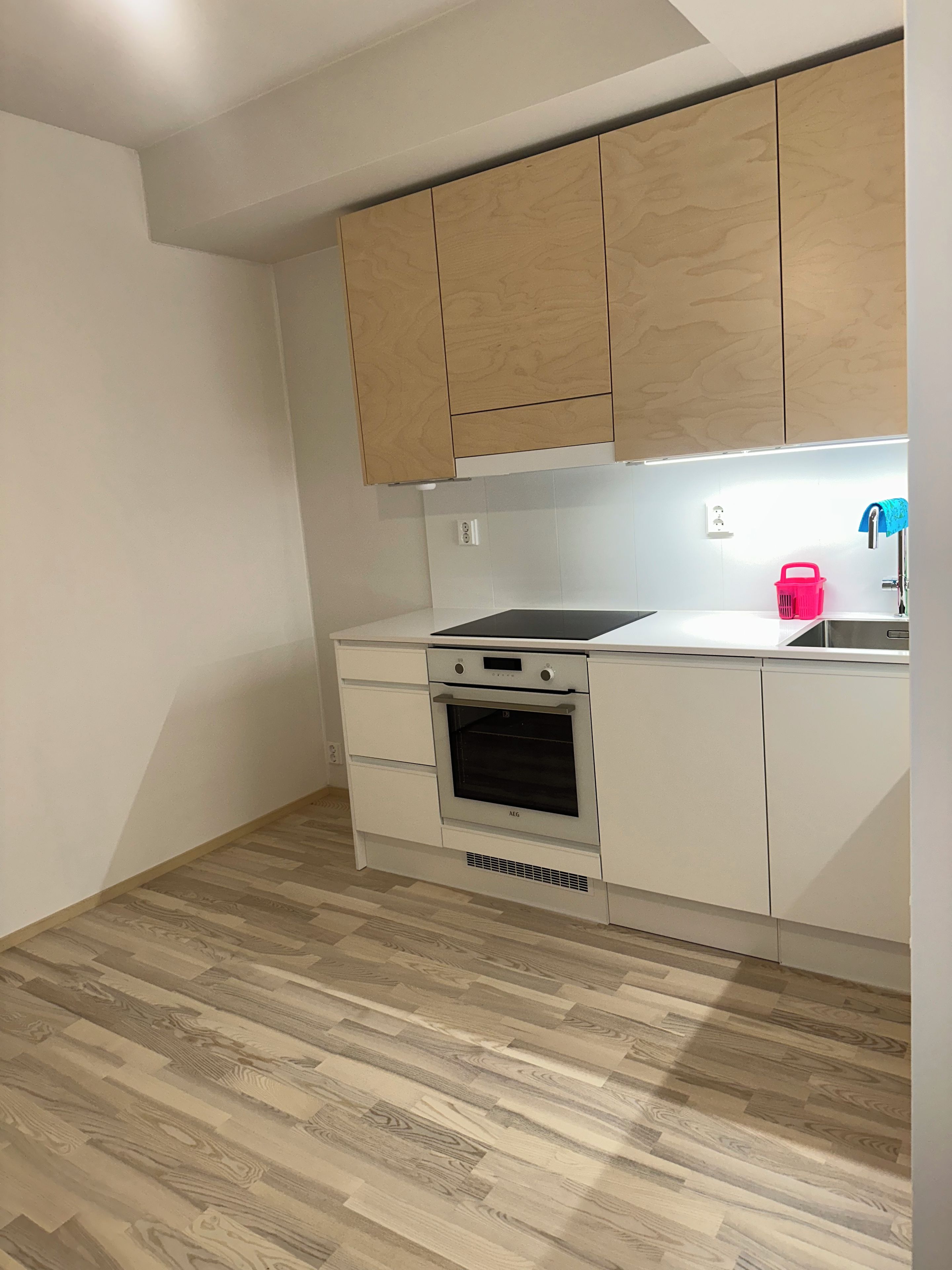A kitchen with white cabinets, a built-in oven, and a wooden floor.