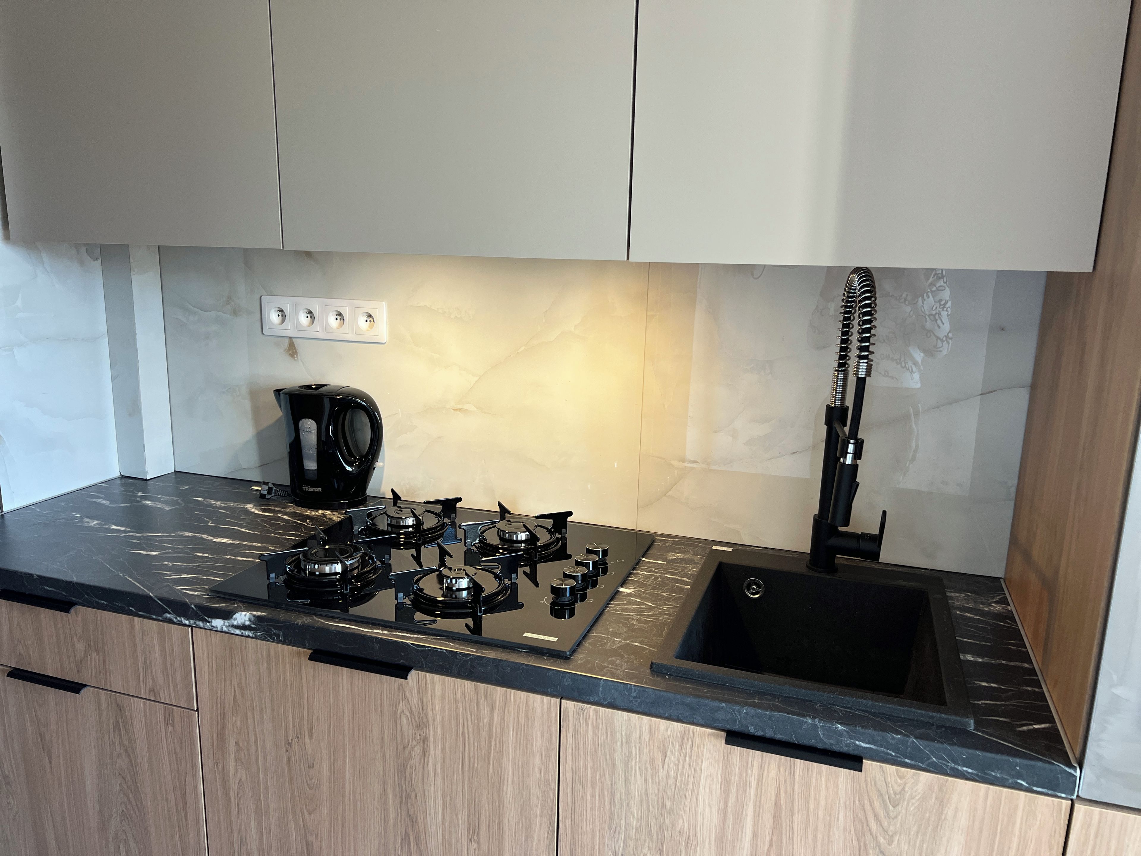 A modern kitchen with a gas stove, a coffee maker, and a sink.