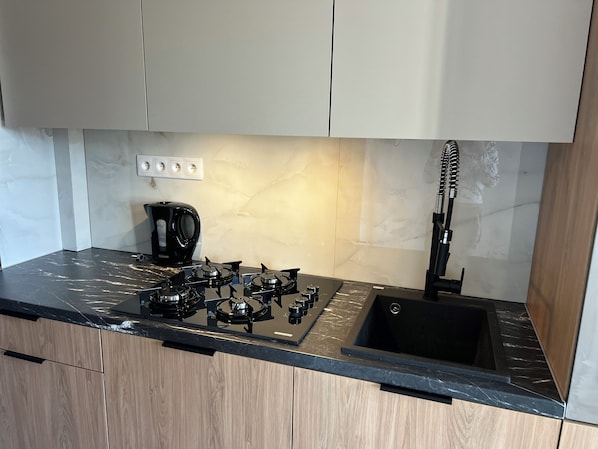 Eine moderne Küche mit Gaskochfeld, Kaffeemaschine und Spüle.