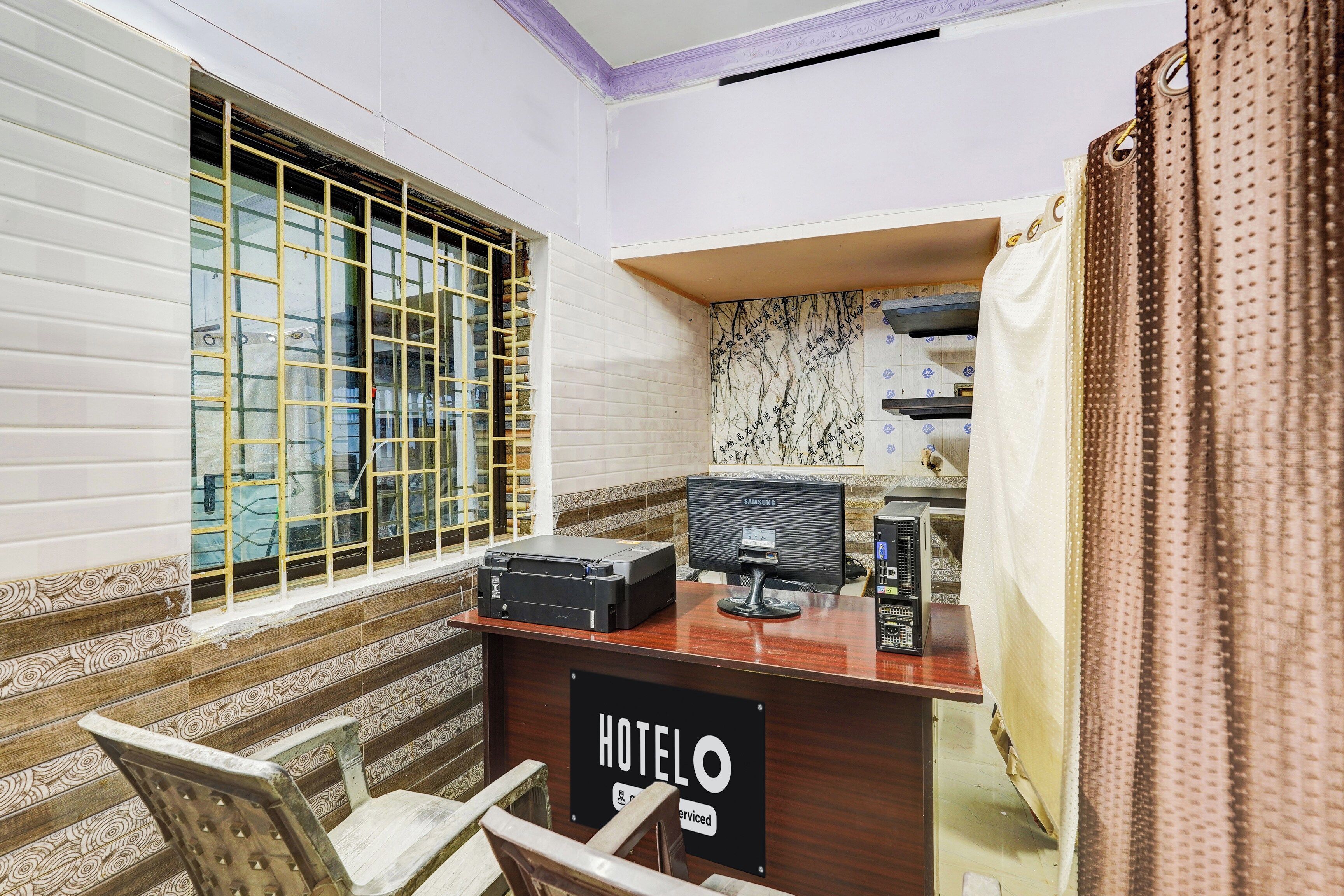 A hotel room with a desk, a chair, a window with bars, and a sign indicating the room is serviced.