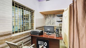 A hotel room with a desk, a chair, a window with bars, and a sign indicating the room is serviced.