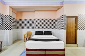 A bedroom with a bed, a wooden door, and patterned walls.