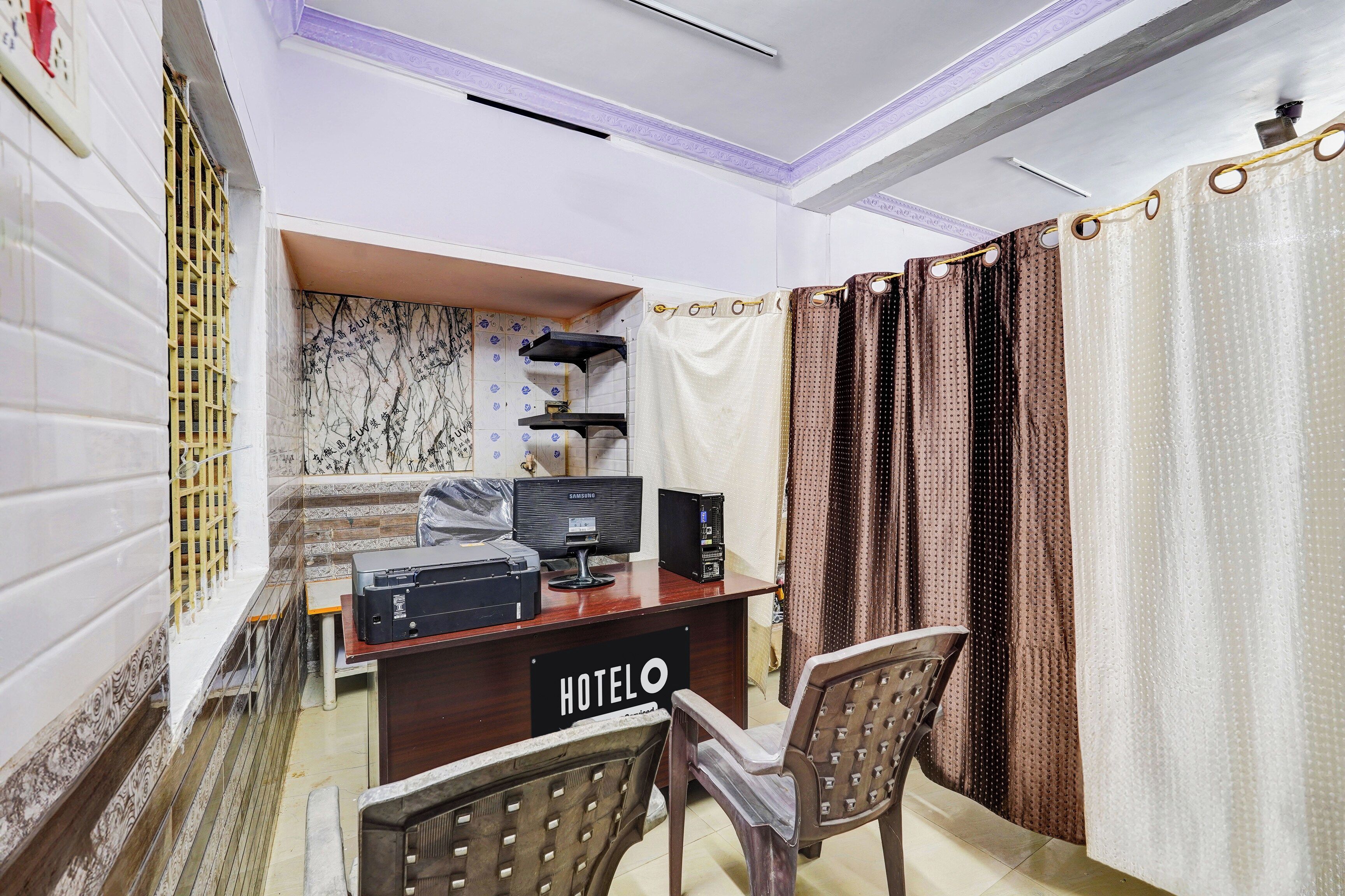 A hotel room with a desk, two chairs, a computer, and a bed.