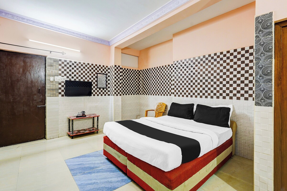 A bedroom with a bed, a small table, a chair, and a television.