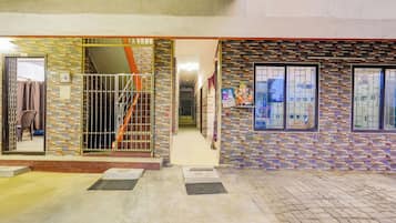 A building entrance with a tiled facade, a metal gate, and a staircase leading to an upper level.