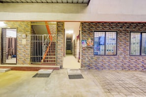 A building entrance with a tiled facade, a metal gate, and a staircase leading to an upper level. - Hotel O VIT Road Vellore (Katpadi)