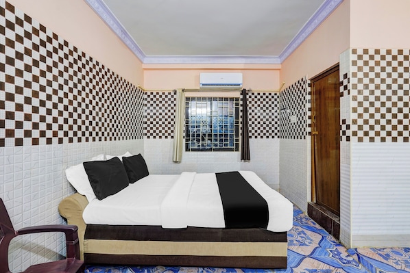 A hotel room with a bed, a window with a view, and checkered wall tiles.