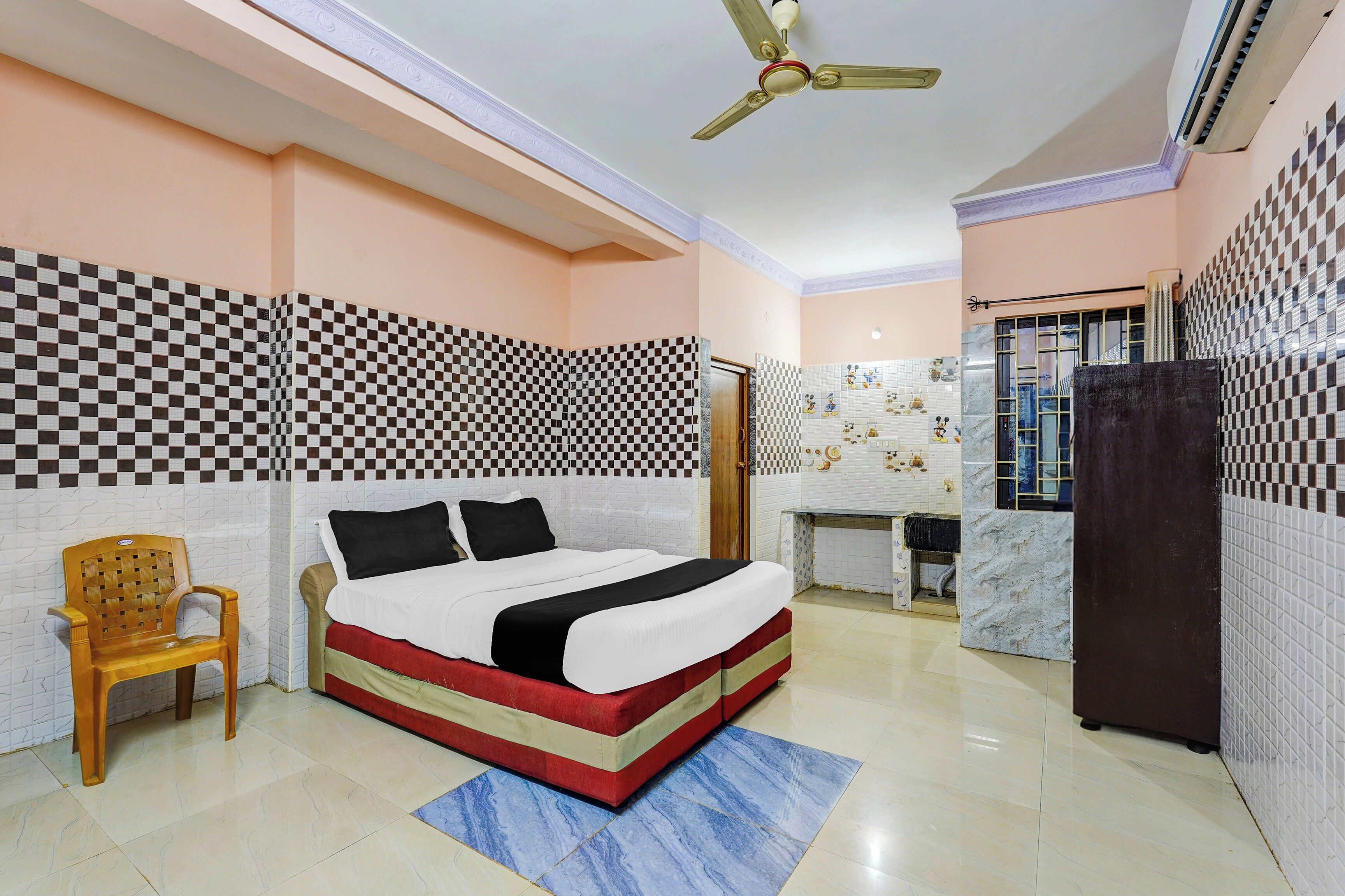 Une chambre d’hôtel avec un lit, un bureau, une chaise et un ventilateur de plafond.