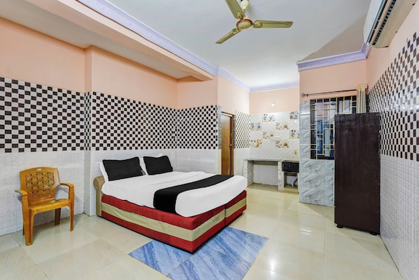 A hotel room with a bed, a desk, a chair, and a ceiling fan.