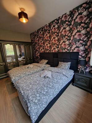 Una camera da letto con un letto grande, carta da parati floreale, una testiera e una lampada da comodino.