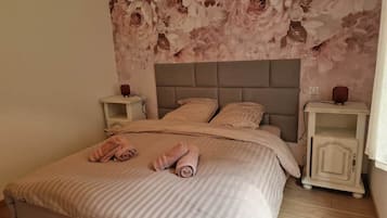 A bedroom with a bed, two nightstands, and a floral wallpaper.