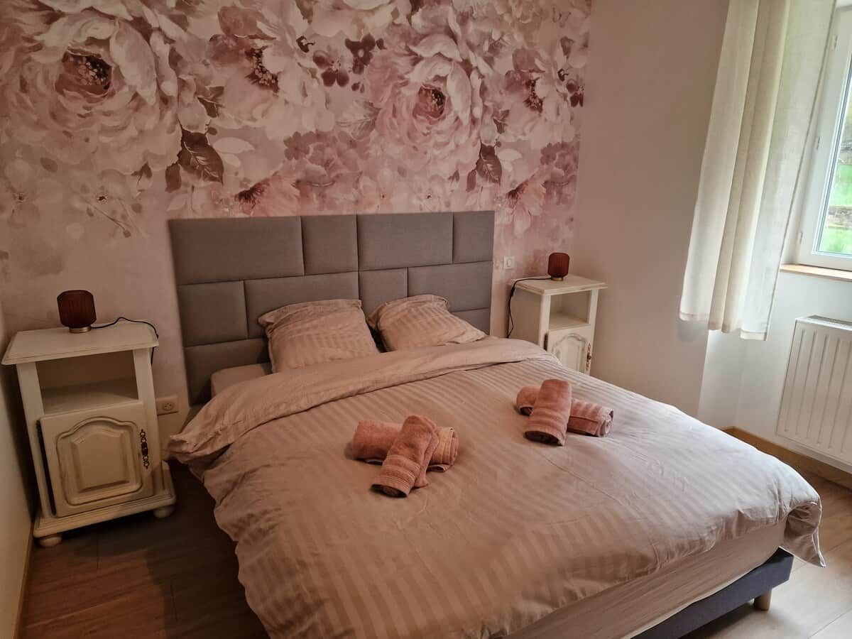Une chambre à coucher avec un lit, des tables de chevet et un papier peint à motifs floraux.