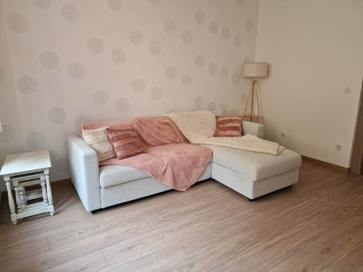 Et værelse med en lysegrå sofa, et lille sofabord og en gulvlampe.