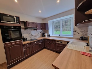 A modern kitchen with built-in appliances, wooden cabinets, and a window providing a view of the outdoors.