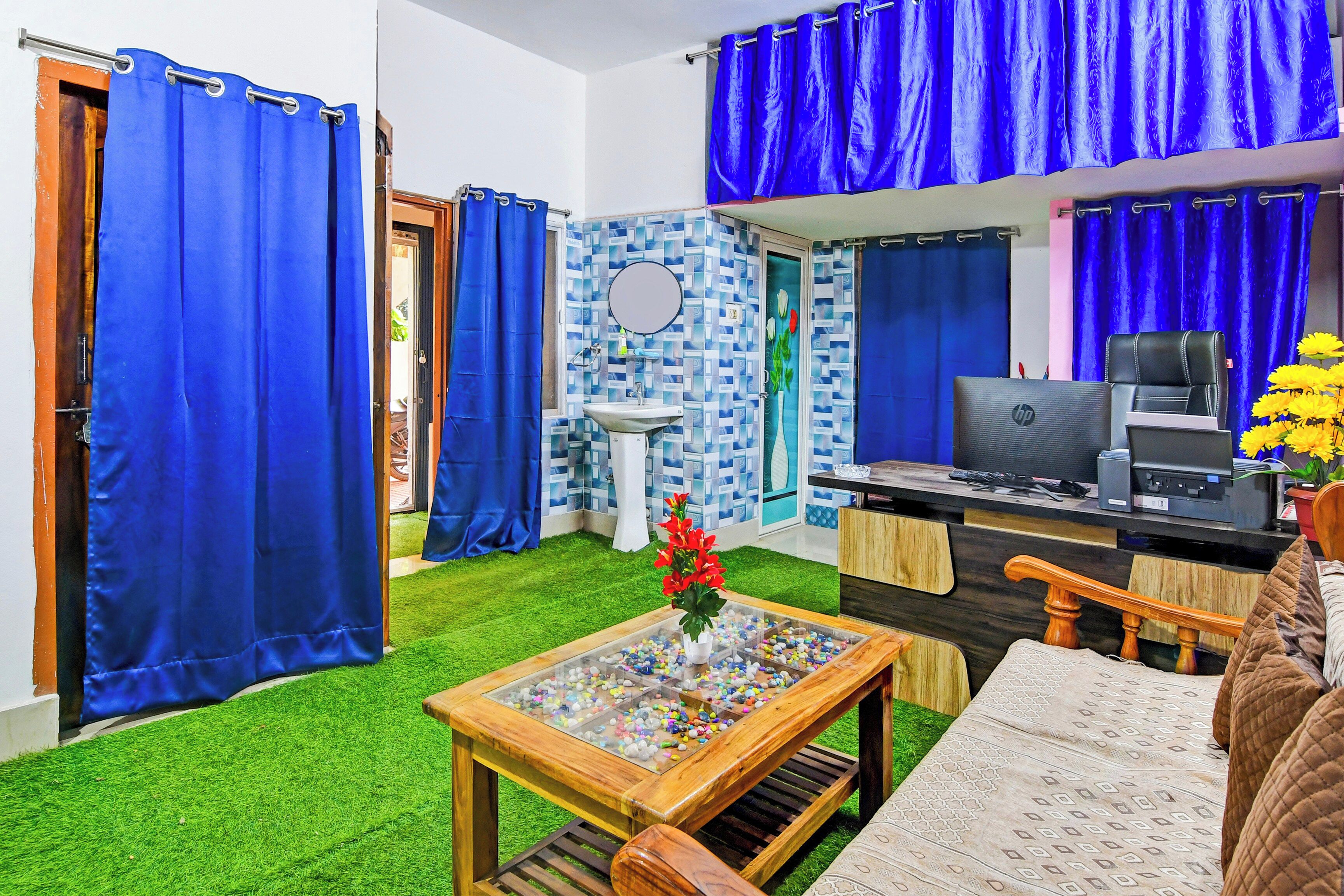 Una habitación con escritorio, silla y una pequeña mesa con un jarrón de flores.