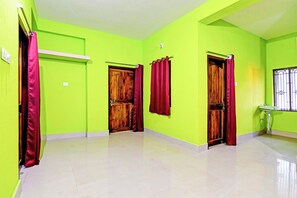 Un pasillo con paredes verdes, puertas de madera y cortinas rojas.