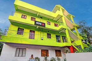 Un edificio de varios pisos con un llamativo letrero de 'OYO Hotel', balcones y una escalera.