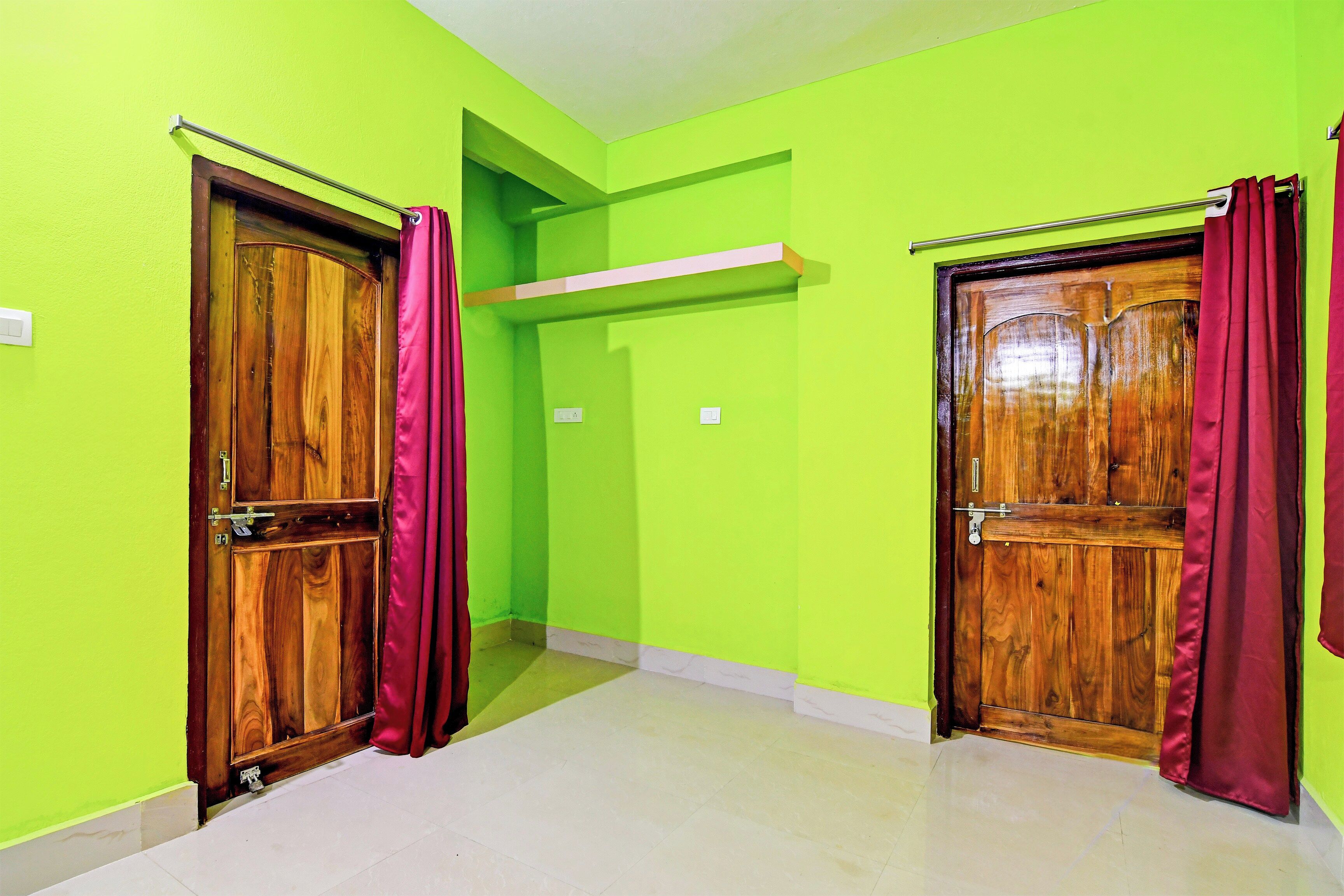 Un pasillo con dos puertas de madera, cada una con una cortina roja, y una pared verde brillante.