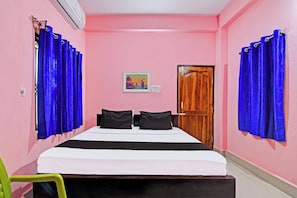 Un dormitorio con una cama, dos almohadas negras, una puerta de madera y cortinas azules.