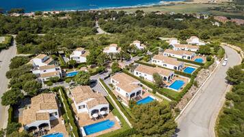 Zona residencial con varias casas, cada una con piscina y entrada pavimentada.