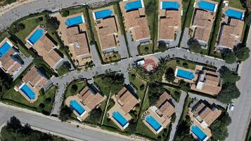 Una zona residencial con varias casas, cada una con piscina y techo de tejas.