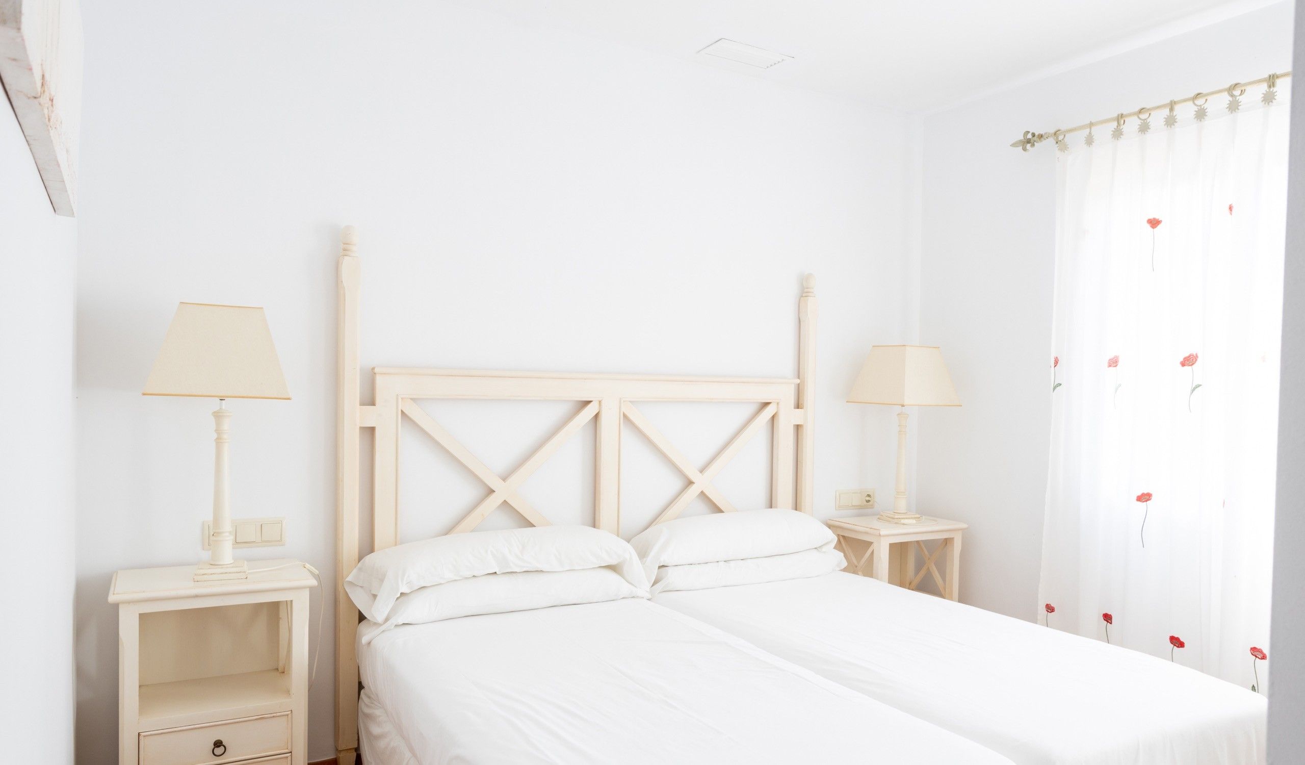 A white bedroom with a bed, two bedside tables, and a nightstand.