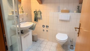 A bathroom with a white sink, toilet, and a glass shower enclosure.