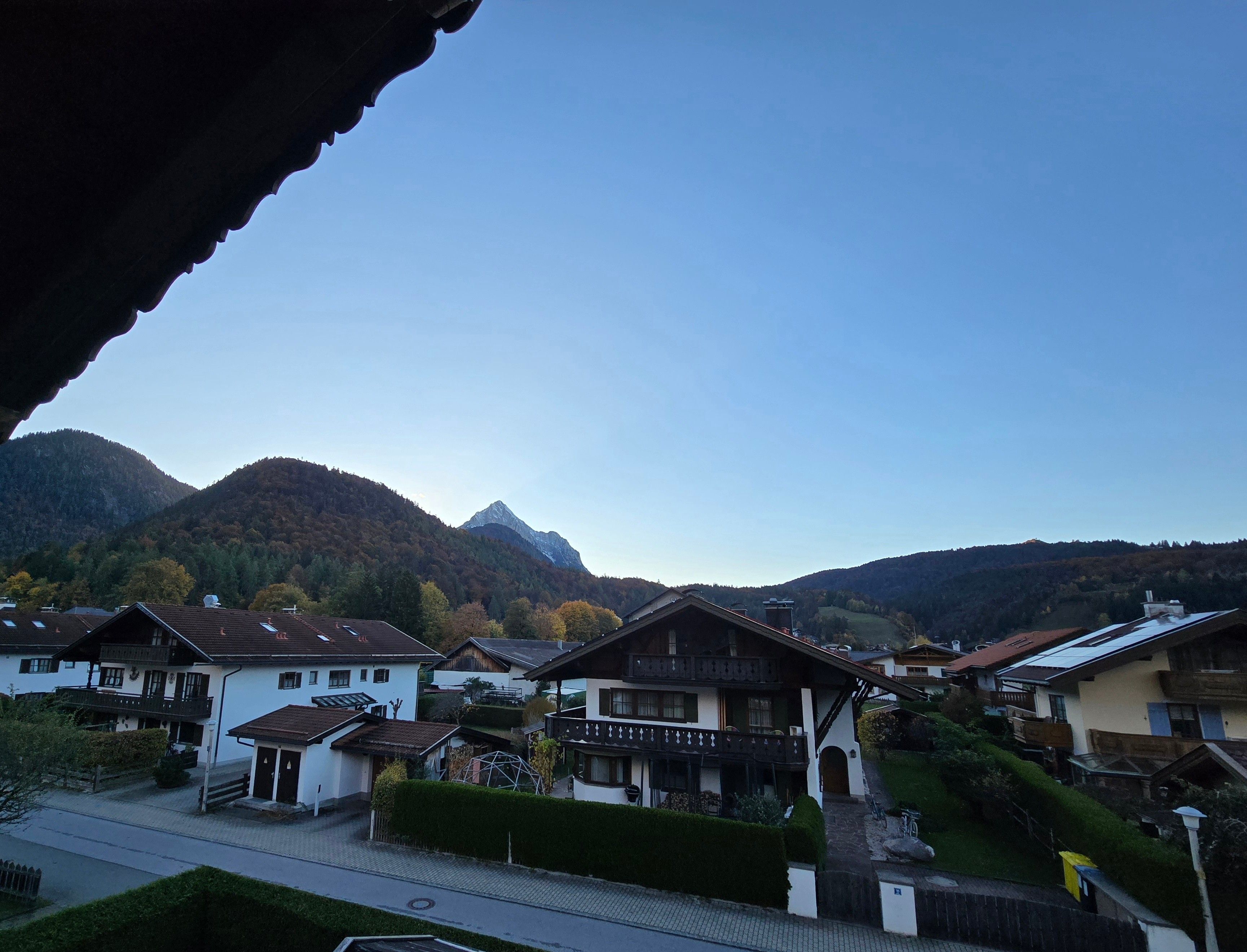 A residential area with houses, a road, and mountains in the background.