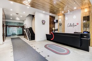 Un área de recepción con mostrador, una escalera y una pared con la palabra 'Collection' escrita.