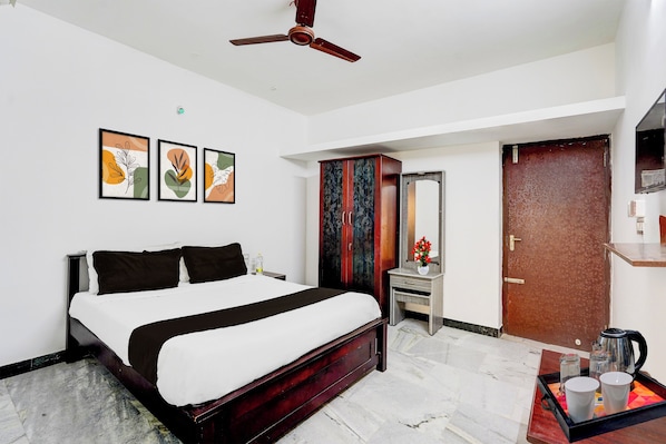 Habitación de hotel con cama, escritorio, espejo y ventilador de techo.