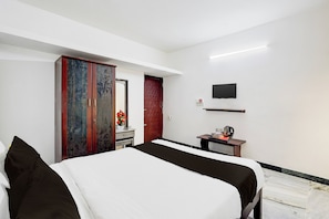 A hotel room with a bed, a wardrobe, a desk with a kettle, a flat-screen TV, and a red accent wall. - Hotel O Katpadi Vellore (Vellore)
