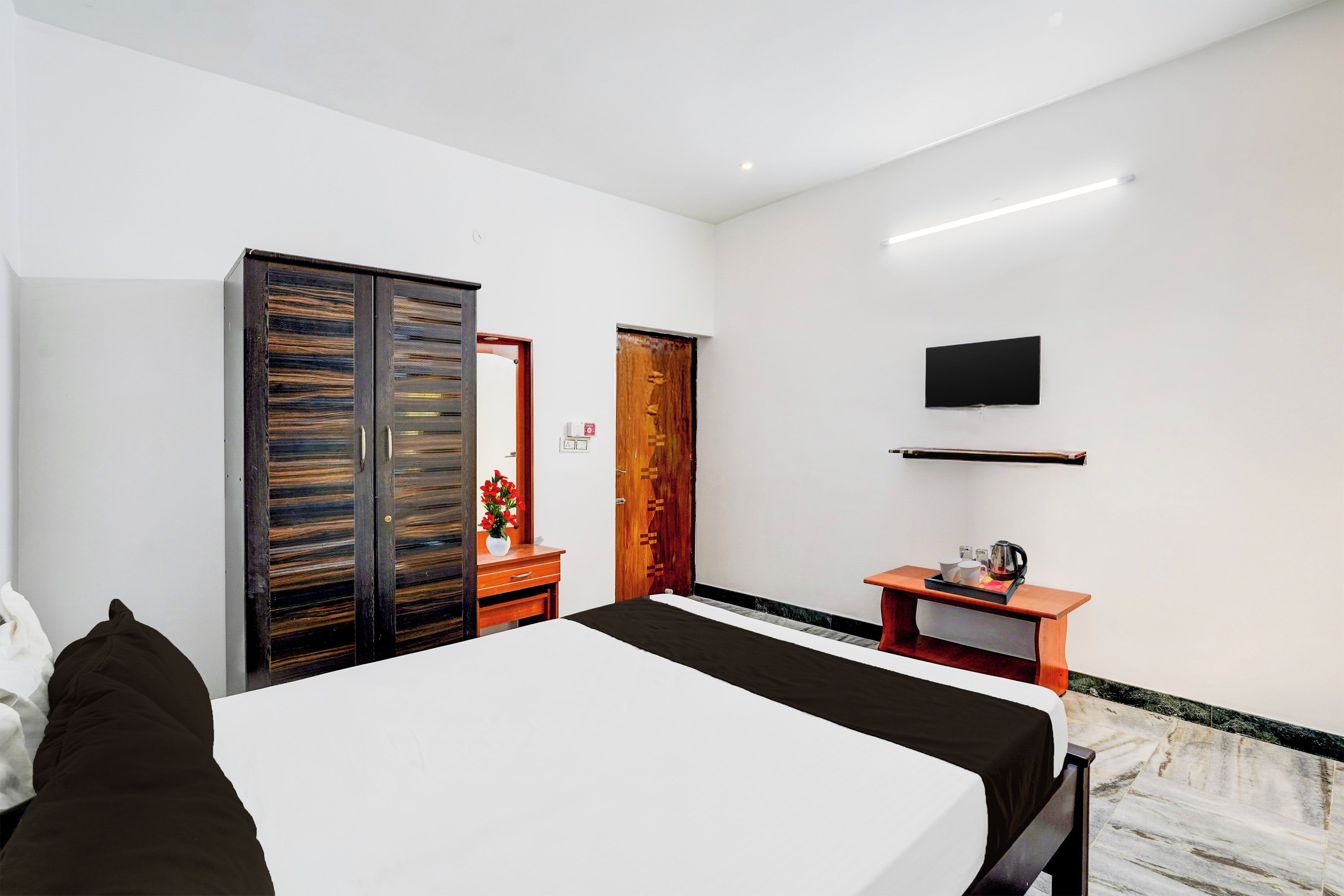 Une chambre d’hôtel comprenant un lit, un bureau avec un téléviseur à écran plat, une armoire et une porte.