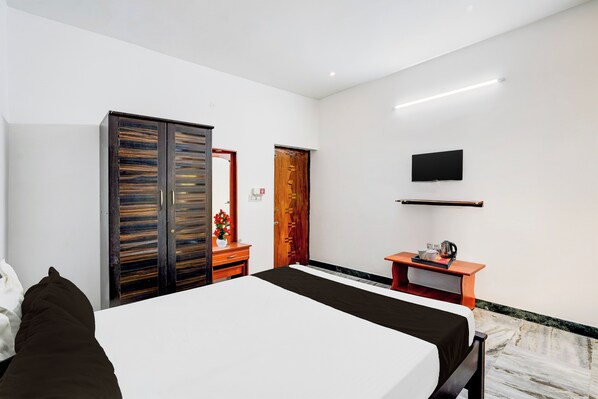 Una habitación de hotel con cama, escritorio con televisor de pantalla plana, armario y puerta.
