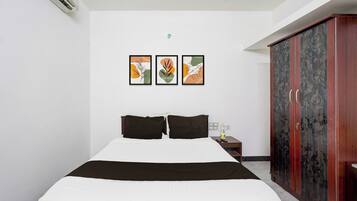 A hotel room with a bed, a wardrobe, and two wall-mounted artworks.