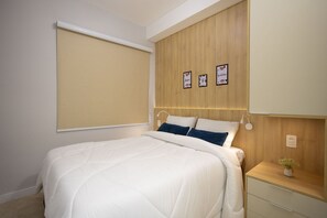 A bedroom with a bed, a bedside table, a nightstand, a wall-mounted shelf, and a window with a blind. - Nex One Sena Madureira (São Paulo)