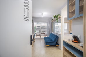 Un salon moderne comprenant un canapé, une table à manger avec des chaises et un coin cuisine avec une machine à café.